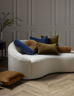 Charlotte velvet pillow in toast, olive, and true blue sit on a cream boucle lounger with other velvet pillows