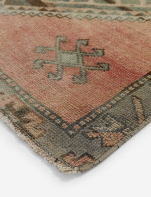 A close-up of Vintage Turkish Runner Rug No. 31 (28 x 1012) reveals geometric patterns in muted pink, green, and beige, with a decorative border and central rectangular motif—a unique, inviting centerpiece for any space.