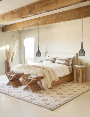 The European Flax Linen white Duvet Set by Cultiver lays on a linen and wooden framed bed in a bedroom with wooden beamed ceilings, a sculptural wooden nightstand, and black jute pendant lights