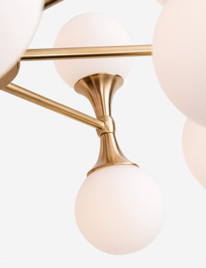 Close-up of the a cone-shaped metal stand and dual-light fixture on the Abernathy gold wheel-like chandelier