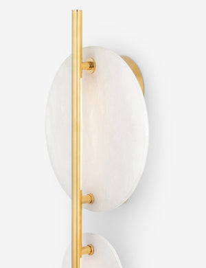 Angled close-up of the largest alabaster disc on the Eleir sconce with antique brass finish