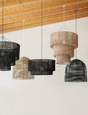 The Chavette three-tiered black jute-wrapped chandelier is hung amongst other jute chandeliers from a sloped wooden ceiling
