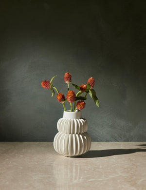 Delilah white ceramic vase featuring two rows of half-moon discs fanned around a tapered body with flowers inside of itDelilah white ceramic vase featuring two rows of half-moon discs fanned around a tapered body with flowers inside of it