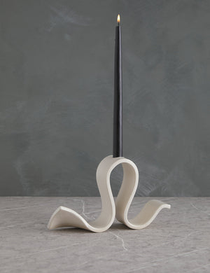 Whit white Candelabra by SIN with an undulating silhouette and a black taper candle